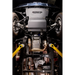 Undercarriage view of a vehicle showing a large gray JUGGERHUNT USA engine cover, yellow suspension arms, exhaust pipes, and mechanical components.