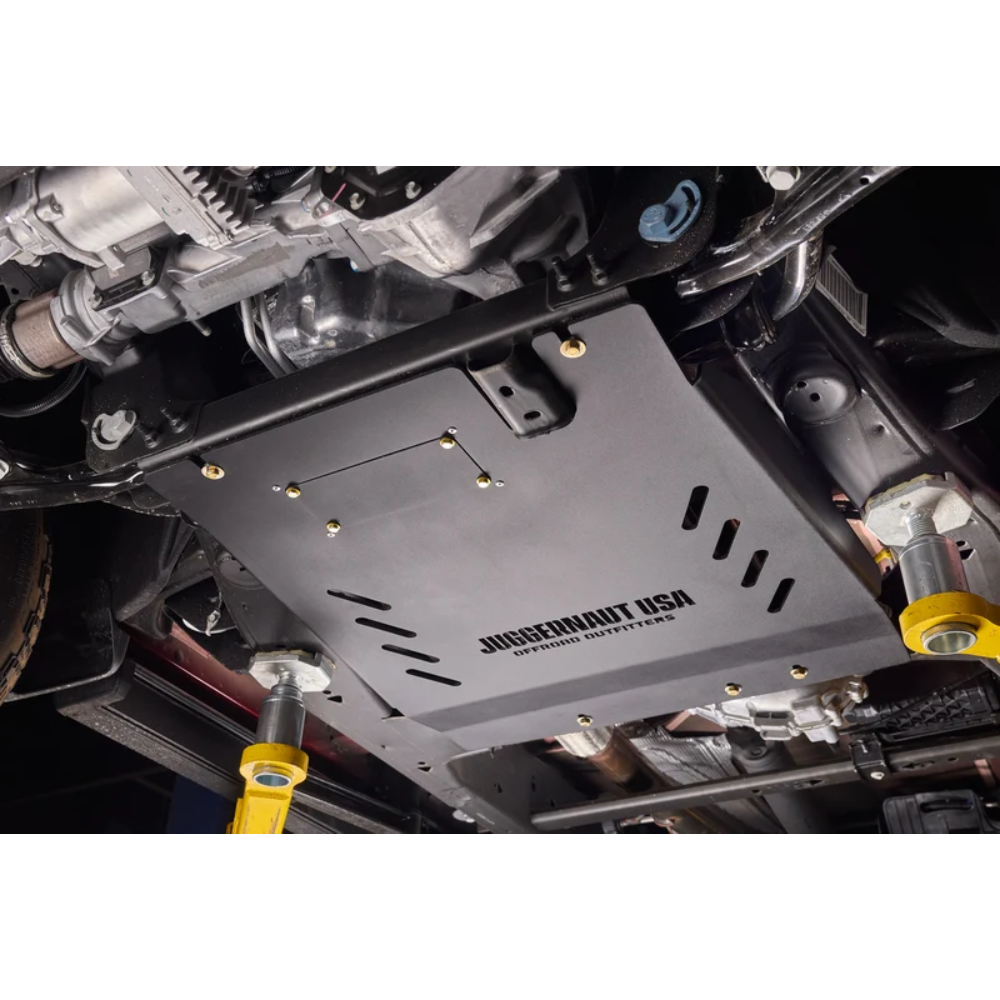 A black metal undercarriage splash shield with 'JUGGERMANT USA' printed on it, installed on a vehicle's underside.