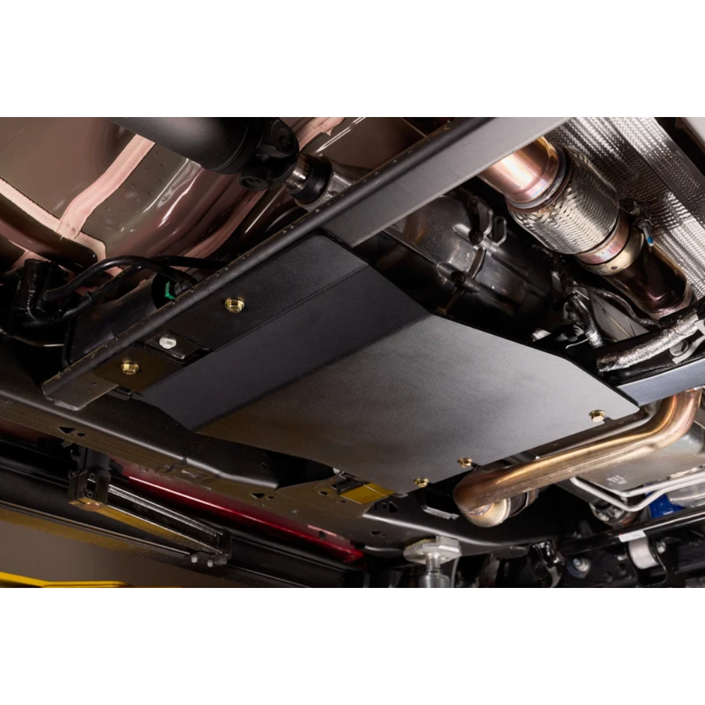 A black metal undercarriage shield plate installed on a vehicle's chassis, shown in a close-up view of the underside of a car.