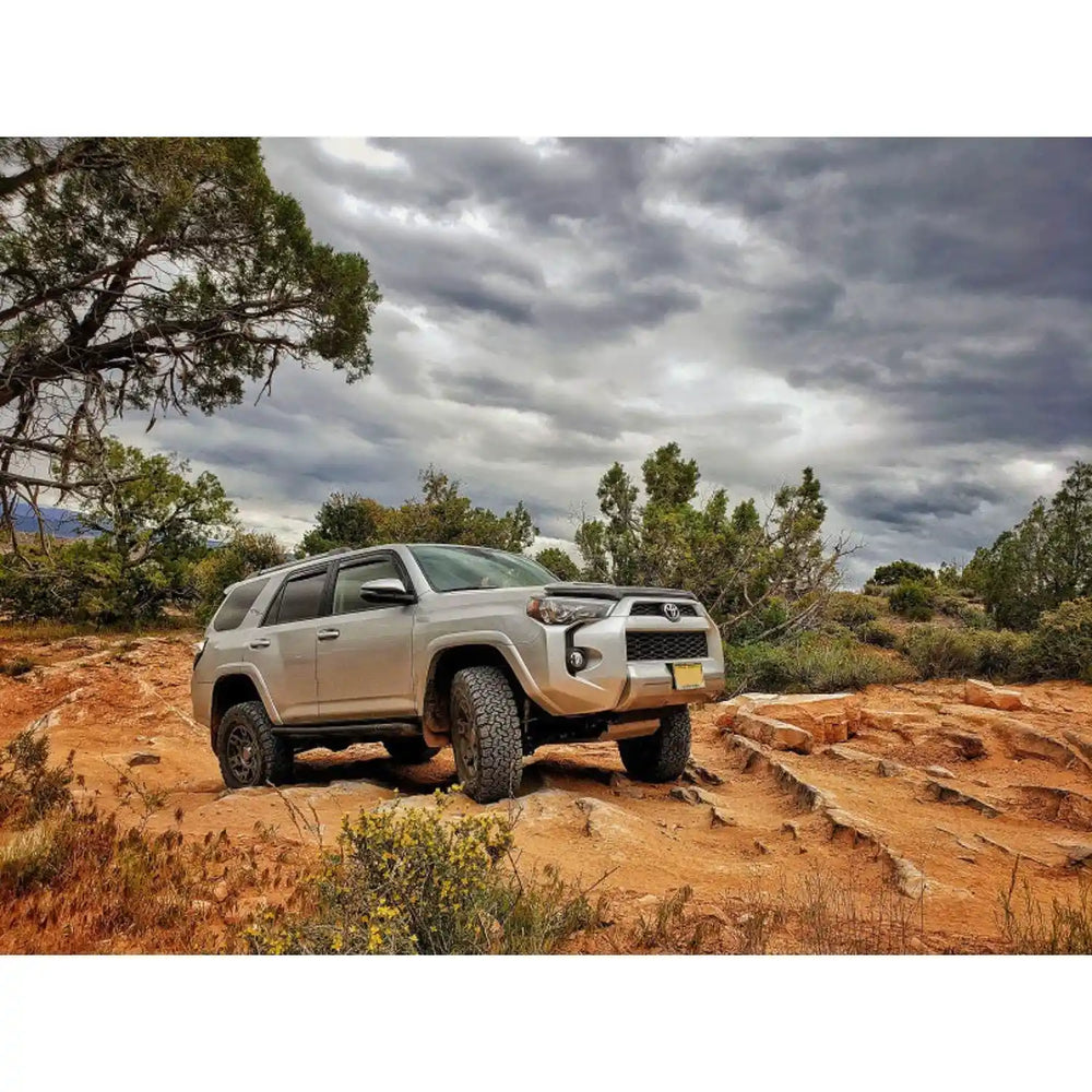 Silver 4runner on a rocky trail with mounted rock sliders by rsg