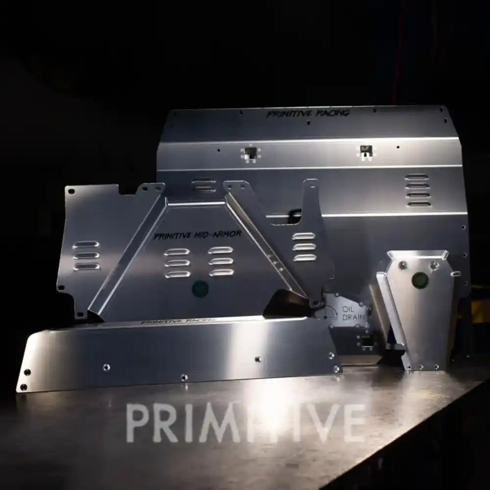 Aluminum skid plats packages on a reflective surface with 'PRIMITIVE' branding.
