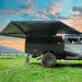 Black off-road vehicle with a large 23zero 270 awning in a grassy field during sunset.