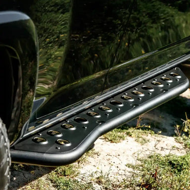 Close-up of a black vehicle step rock slider with a natural outdoor background