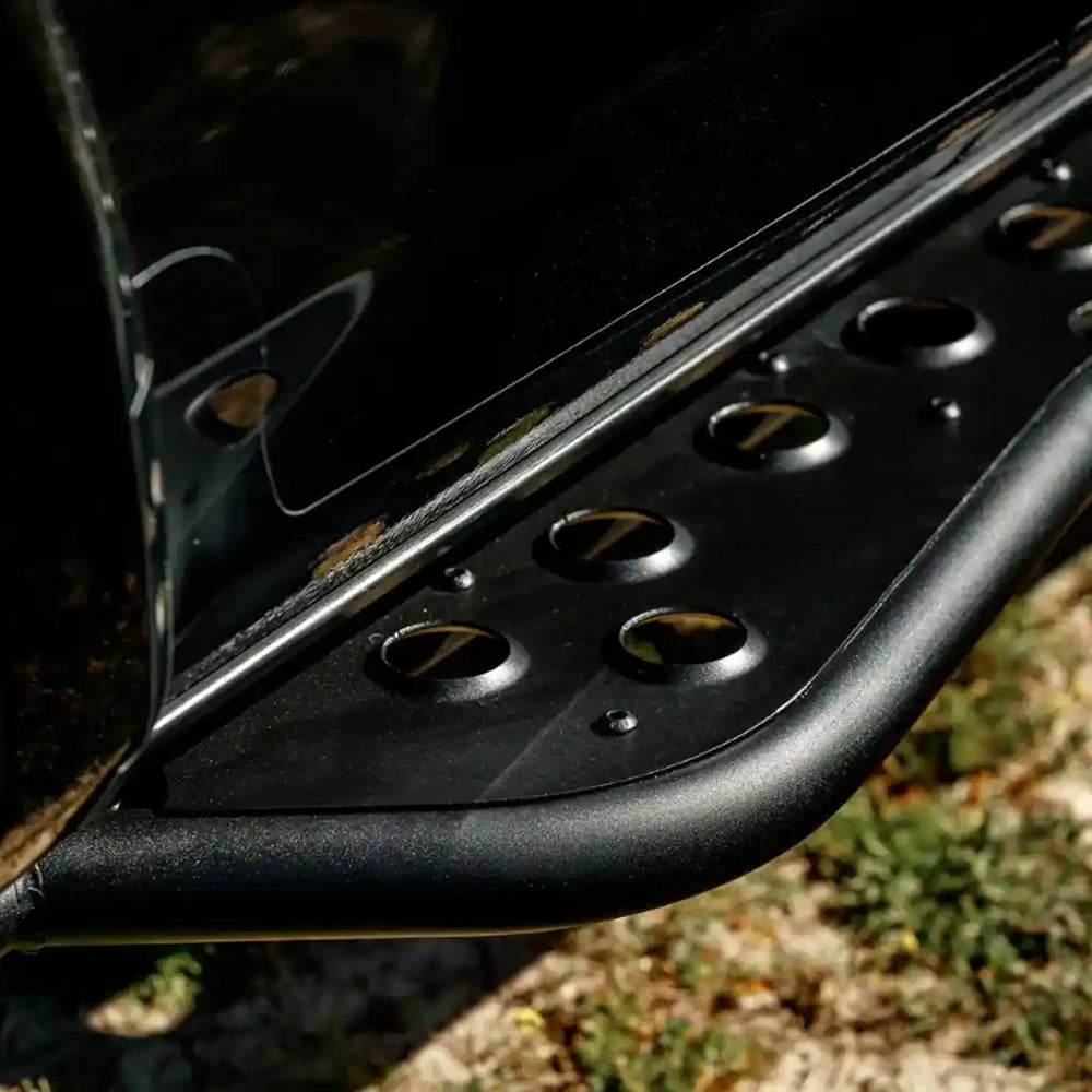 Close-up of a black car step with circular cutouts on a natural background