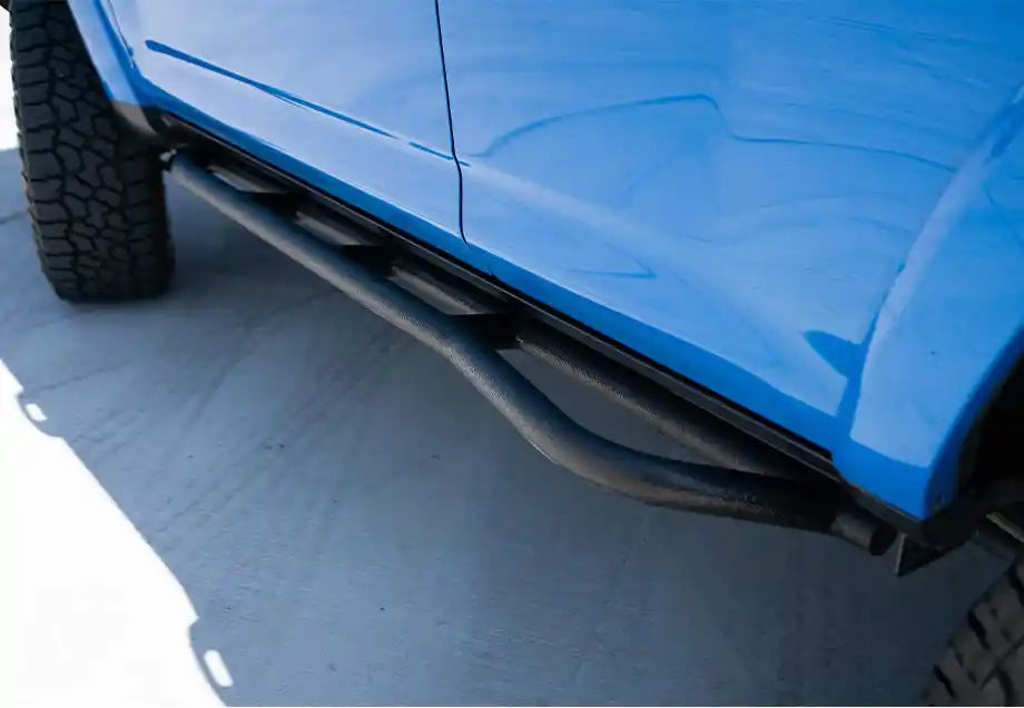 Side view of a blue 4runner with a black running board on a gray surface