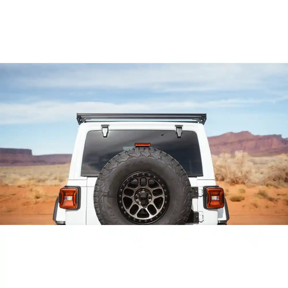 Back view of the mounted Starlight roof rack on a white off-road JLU with a tire on a desert landscape