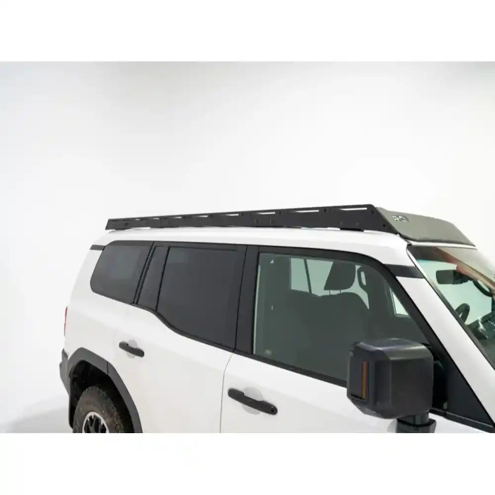 Angled profile of black RCI full-length rack on white Land Cruiser highlighting low-profile design