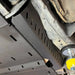 Black RCI catalytic guard installed mid-underbody with visible hardware and exhaust routing