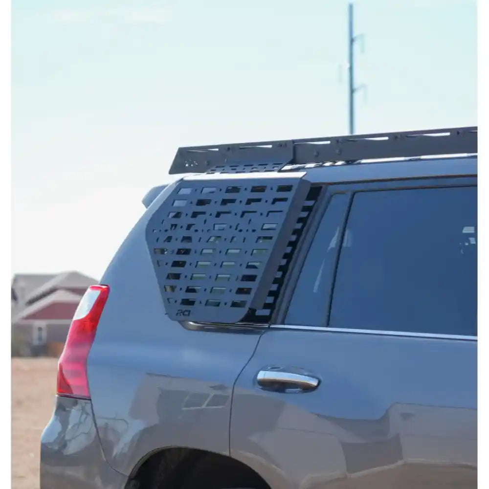 Black RCI side Molle panel mounted on Toyota 4Runner roof rack, rear quarter view with rock backdrop.