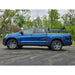 Blue Honda truck with a height adjustable bed rack on a paved road with trees in the background