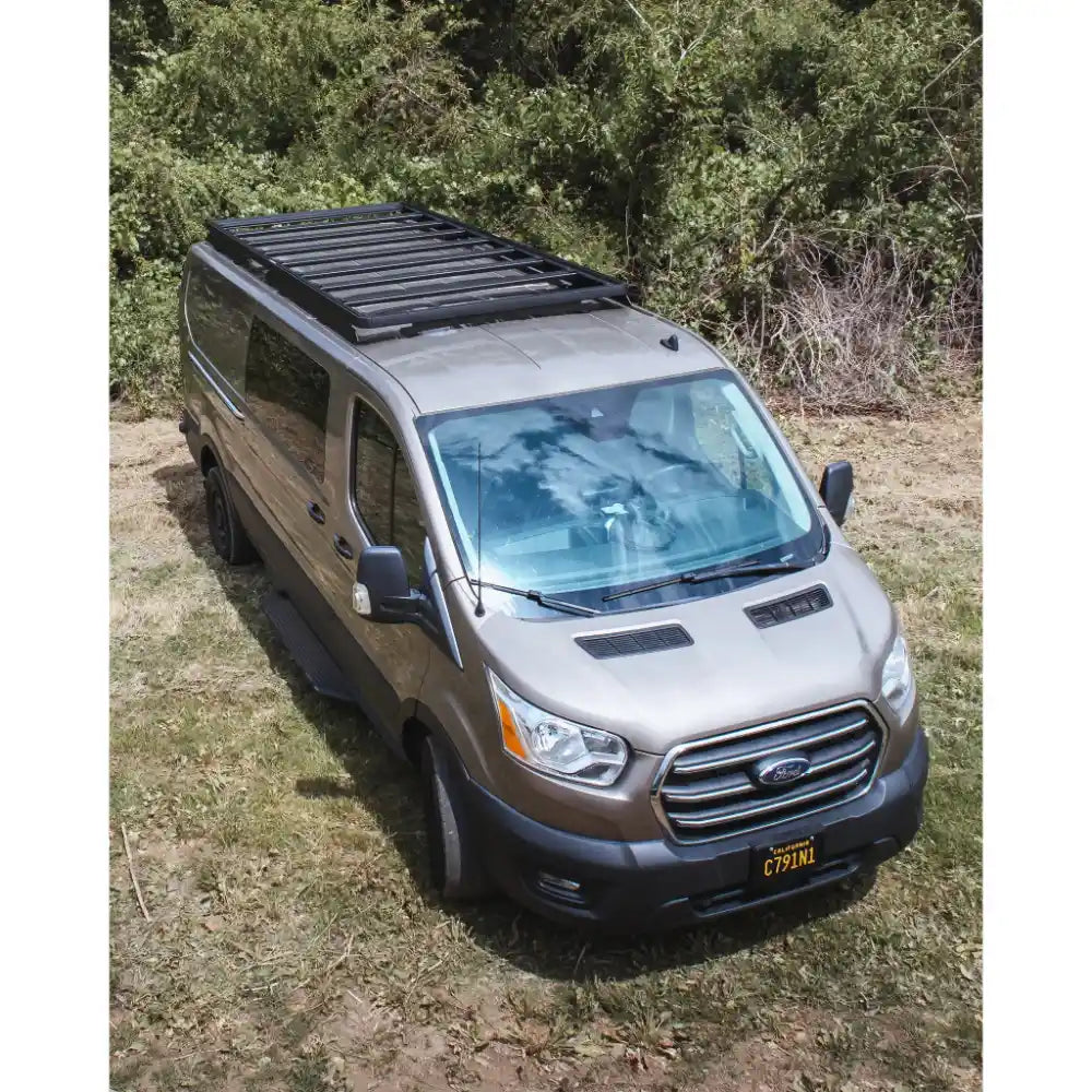 Bronze Ford van with a roof rack in a natural setting