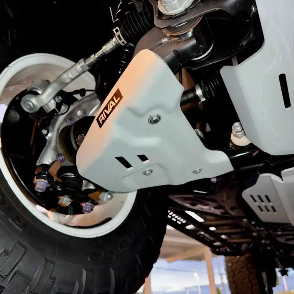 Close-up: RIVAL white skid protecting lower control arm near wheel
