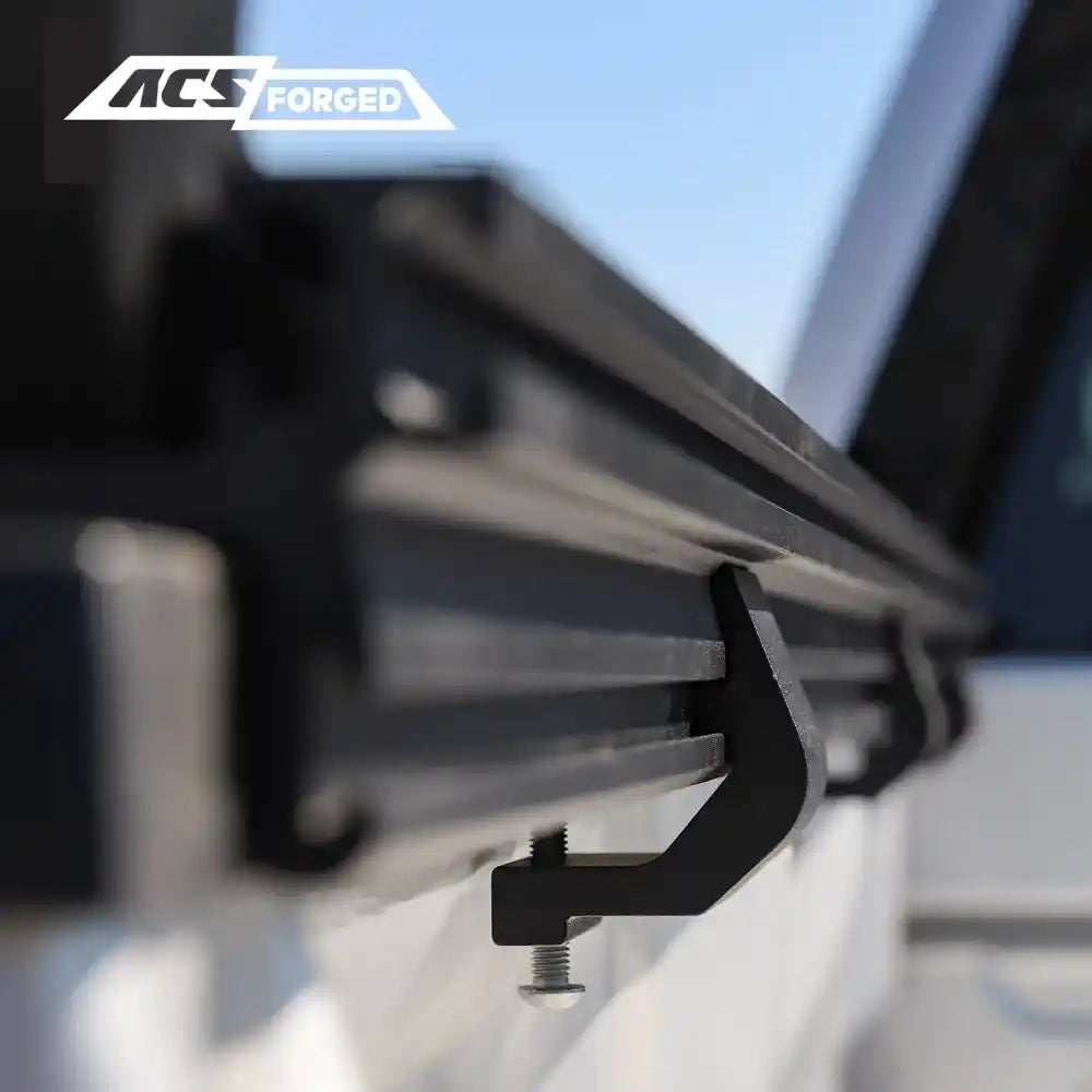 Close-up of a black metal bed rail system on a Toyota with 'ACS Forged' branding.
