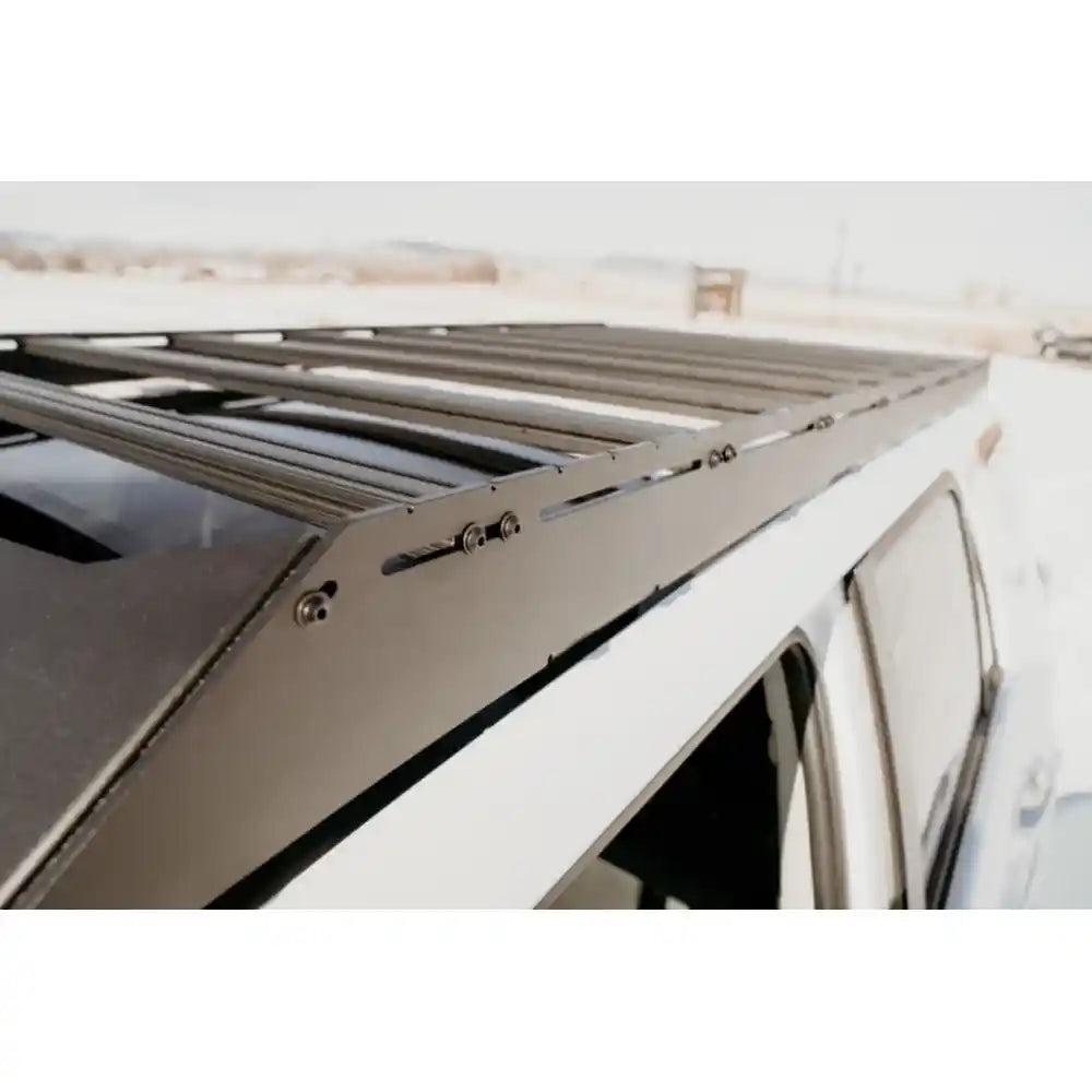 Close-up of black RCI aluminum roof rack showing sturdy side rails, cross slats, and mounting bolts on white 4Runner roof