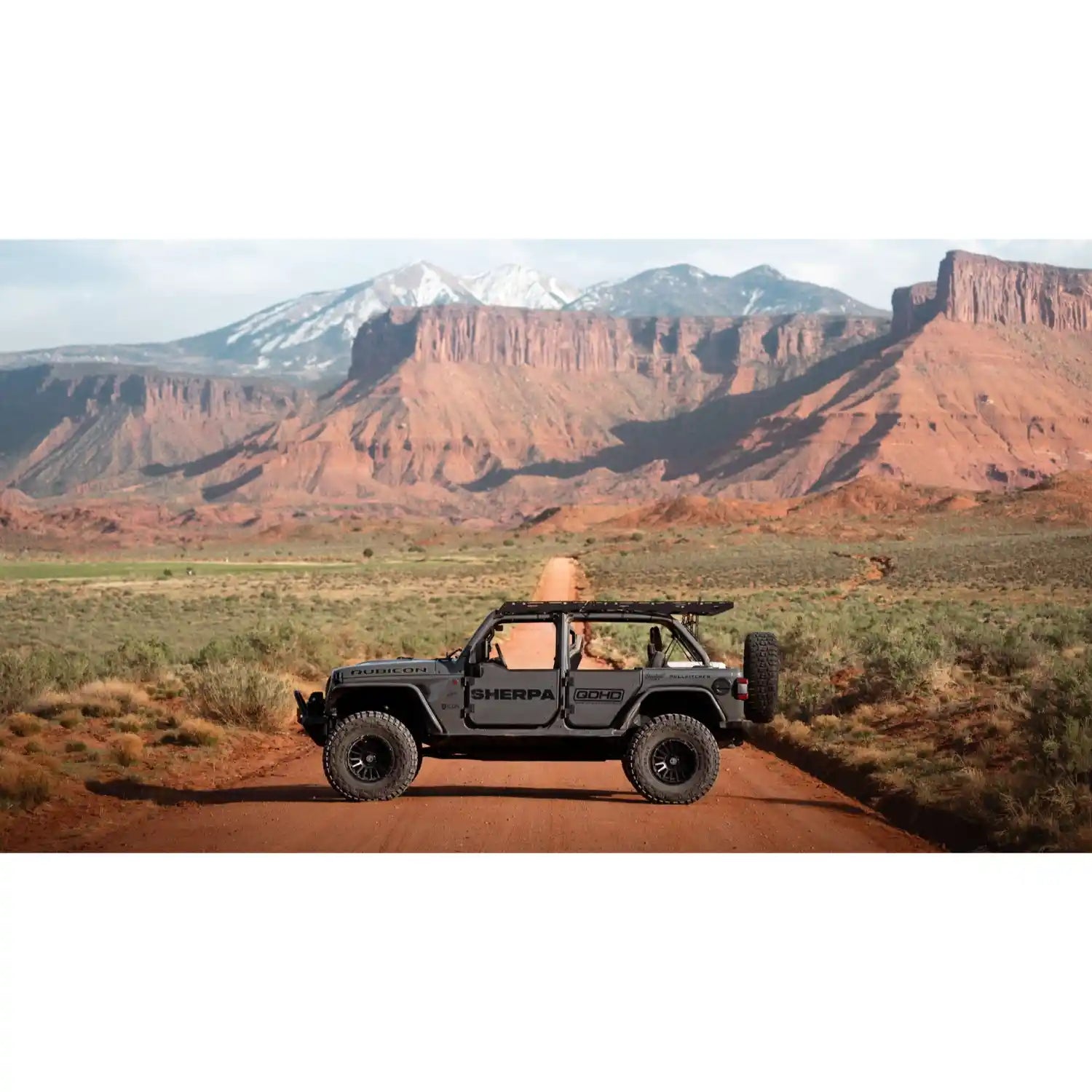 Side view of Sherpa rack on Black Jeep Wrangler on a dirt road with desert landscape and mountains in the background