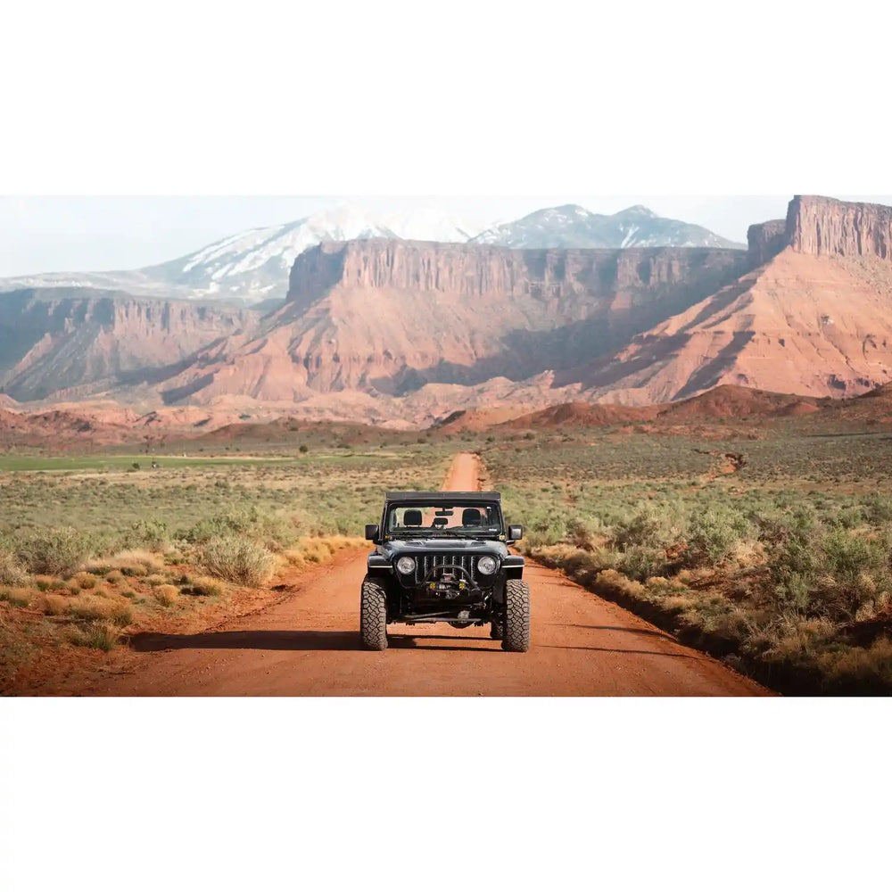 Front view of gladiator with mounted QDHD rack on a dirt road with desert landscape and mountains in the background