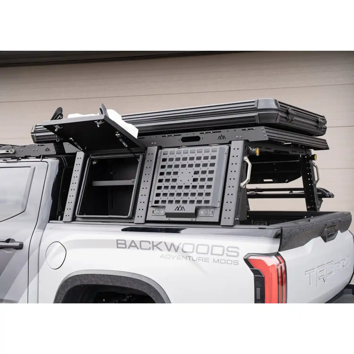 Aluminum truss-style bed rack mounted on a Tacoma carrying a rooftop tent and gear