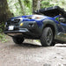 Blue Crosstrek with mounted front skid plate and with a roof rack parked on a dirt path in a forest