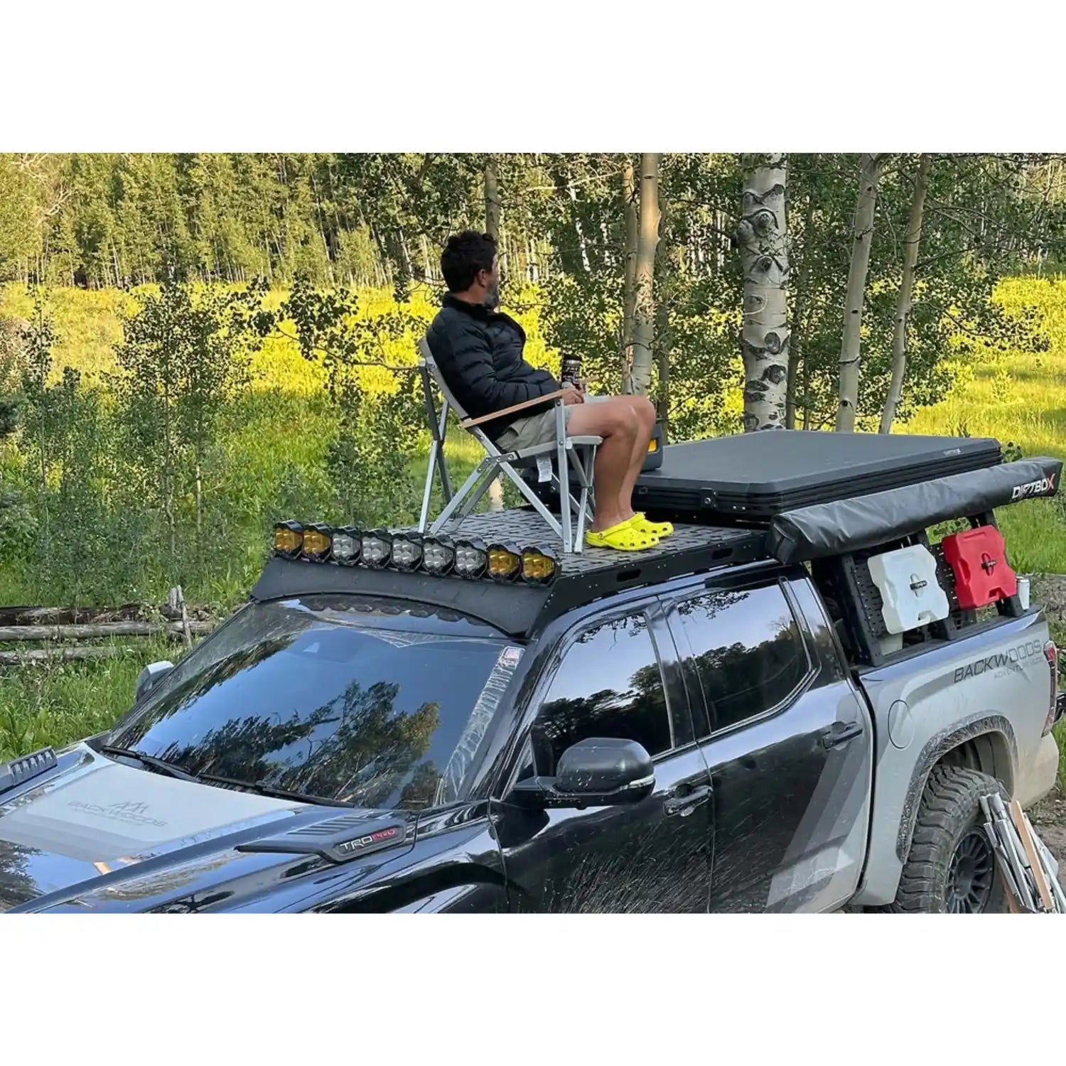 Person sitting on a chair on top of the roof rack to show its durability