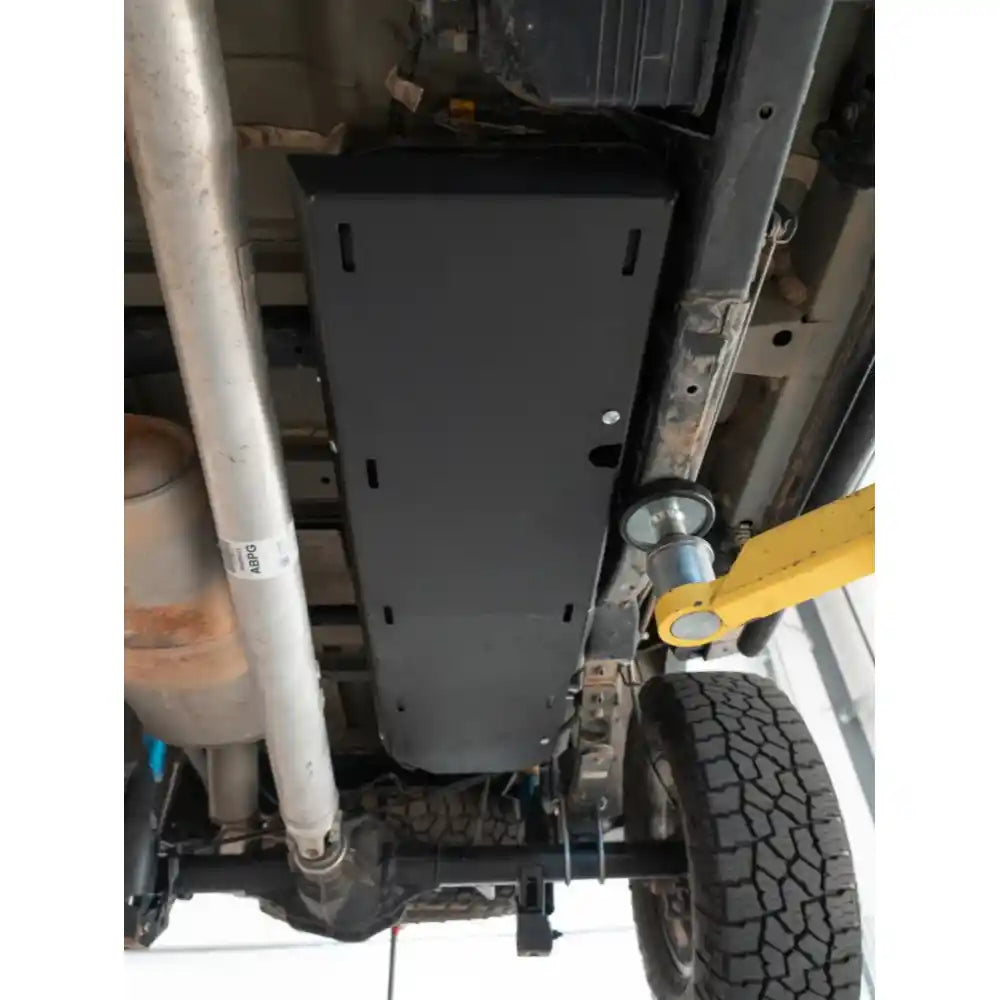 Detailed view of black RCI fuel tank skid plate mounted with visible hardware and frame contact