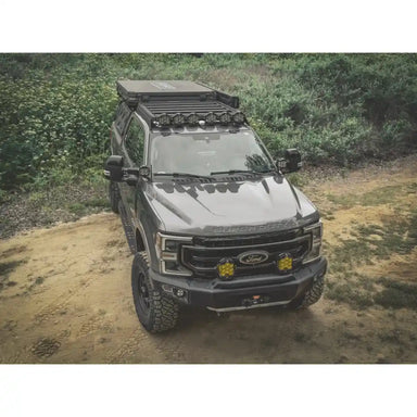 Ford truck with installed Leitner Designs roof rack on a dirt road with a forest background