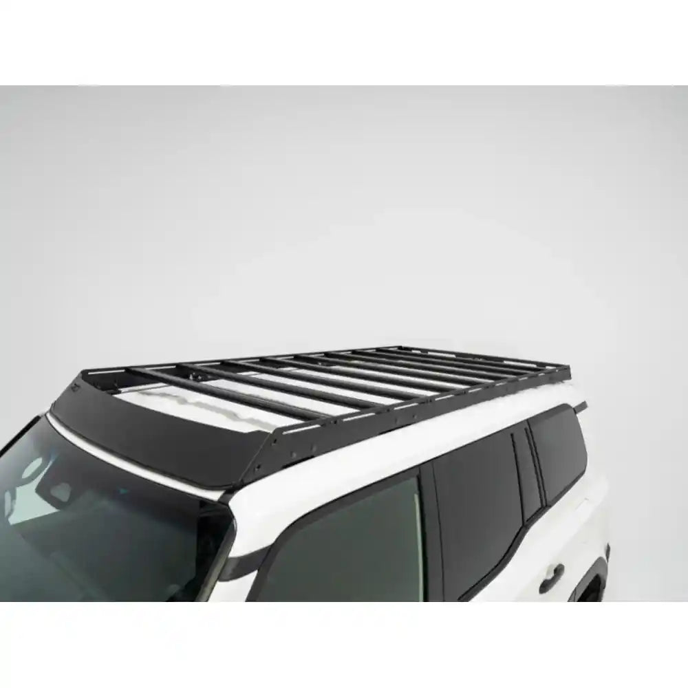 Front-roof perspective of black RCI rack crossbars installed on white Land Cruiser in bright light