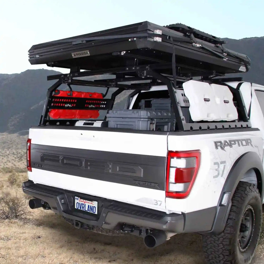 White Ford Raptor truck with an open discovery rack and storage compartments in a desert setting.