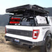 White Ford Raptor truck with an open discovery rack and storage compartments in a desert setting.