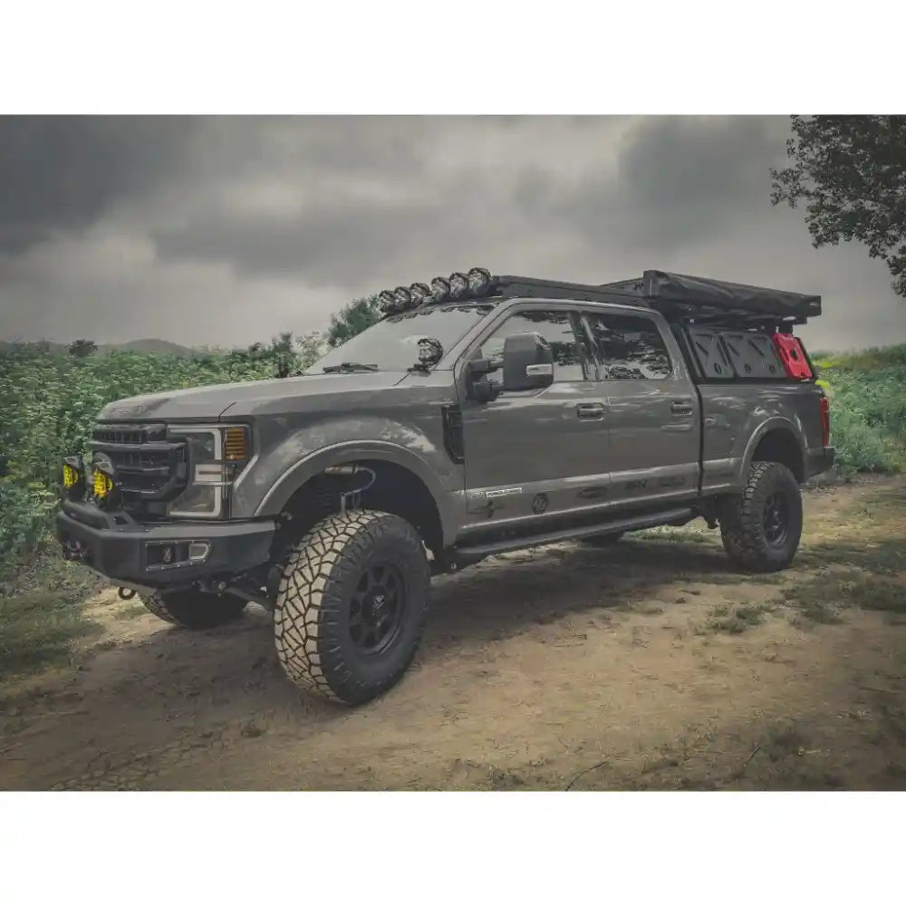 Gray ford with fully loaded Active cargo system on a dirt road with a cloudy sky