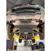 A heavy-duty silver underbody shield with 'JUGGERNAUT USA OFFROAD SUPPITERS' printed on the front, installed on the underside of a lifted black Chevrolet truck on a yellow hydraulic lift inside a garage.