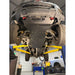 A heavy-duty black underbody shield for a truck, branded 'JUGGERNAUT USA', installed on the bottom of a lifted vehicle in a garage setting.