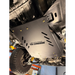 A black metal undercarriage shield with the text 'JUGGERNAUT USA' and 'ENGINEERED OUTSIDE' printed on it, installed on a vehicle undercarriage.