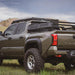 Toyota Tacoma truck with workhorse bed rack and off-road tires in a grassy field