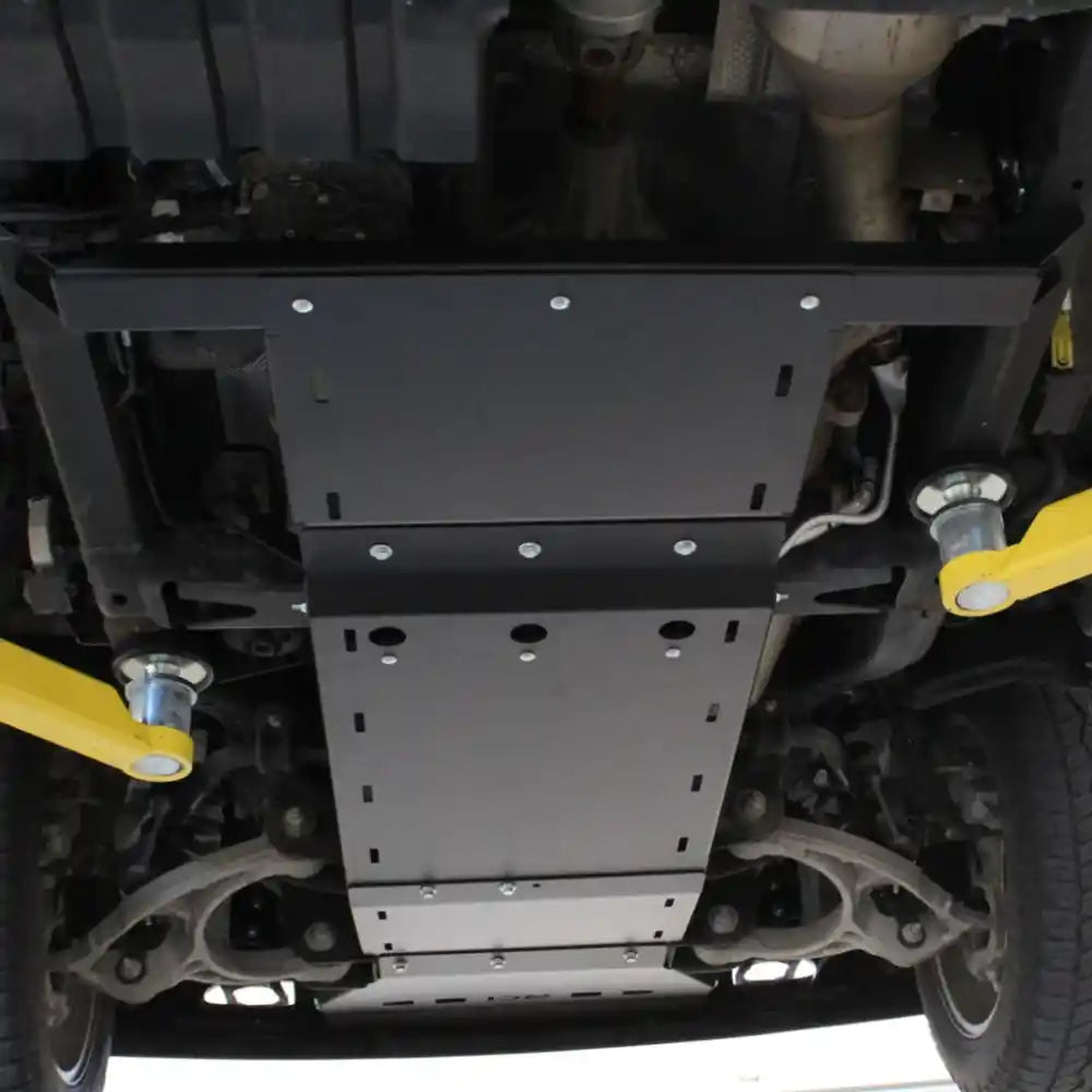 Mid-section transfer case skid plate installed with yellow suspension components visible