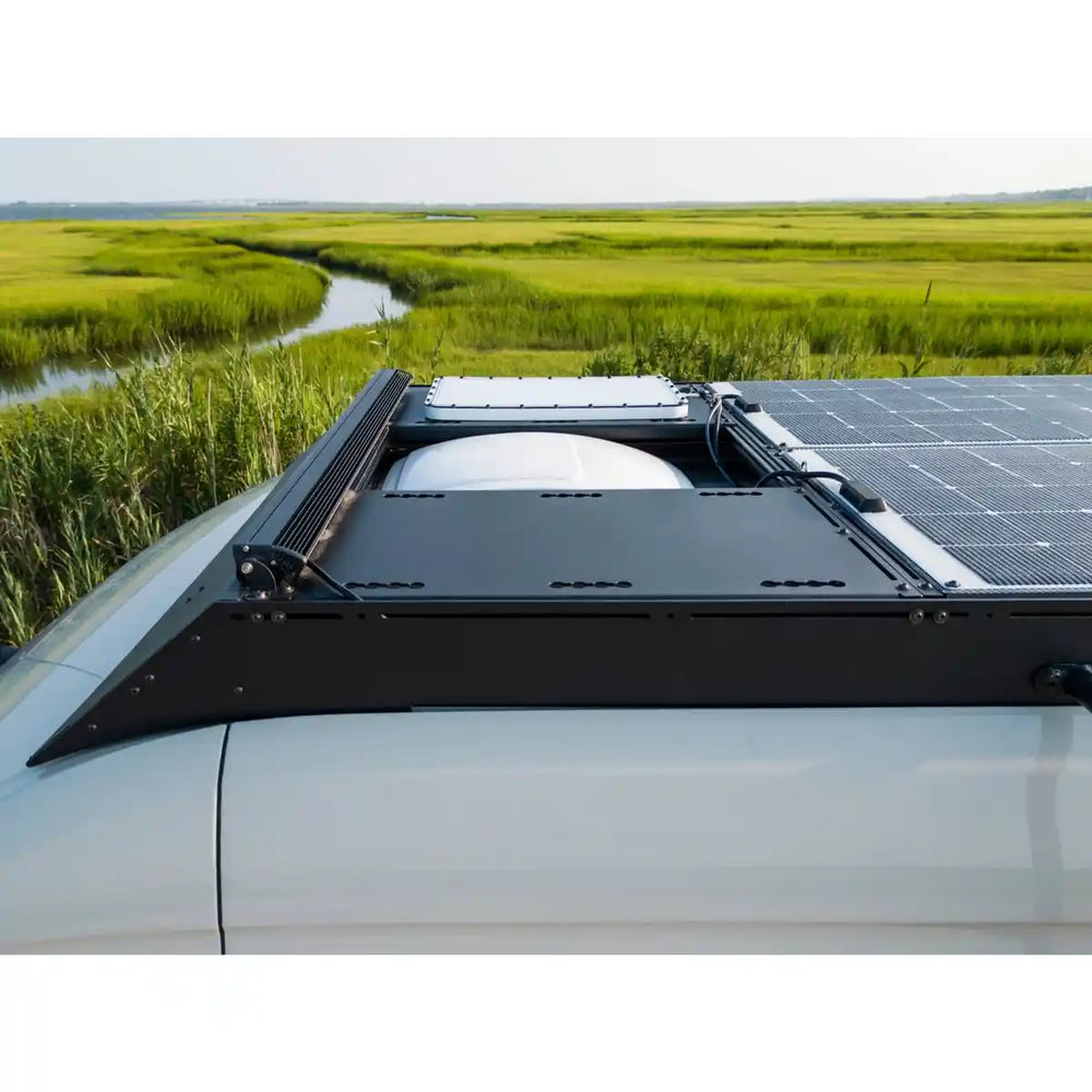 Solar panel on a vehicle roof with a scenic background of green fields and a river.