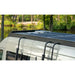 Solar panel on a sprinter roof rack with a scenic background of trees and water.