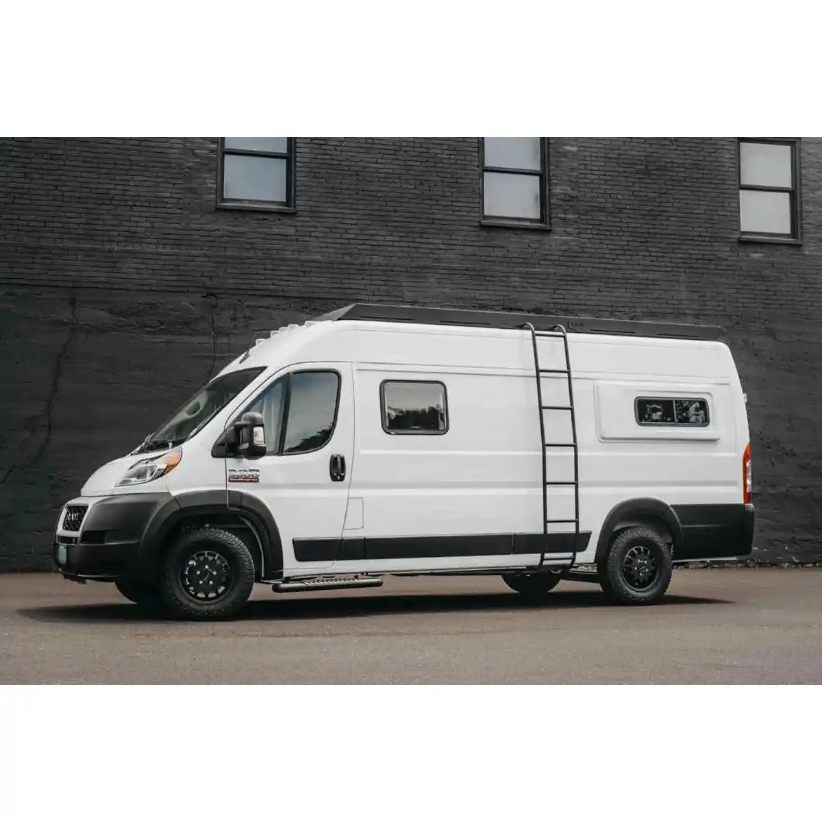 White van with black accents parked in front of a brick wall