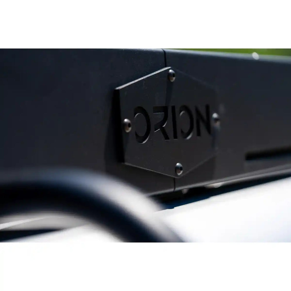 Close-up of a black metal bracket with 'Orion' branding on a blurred background
