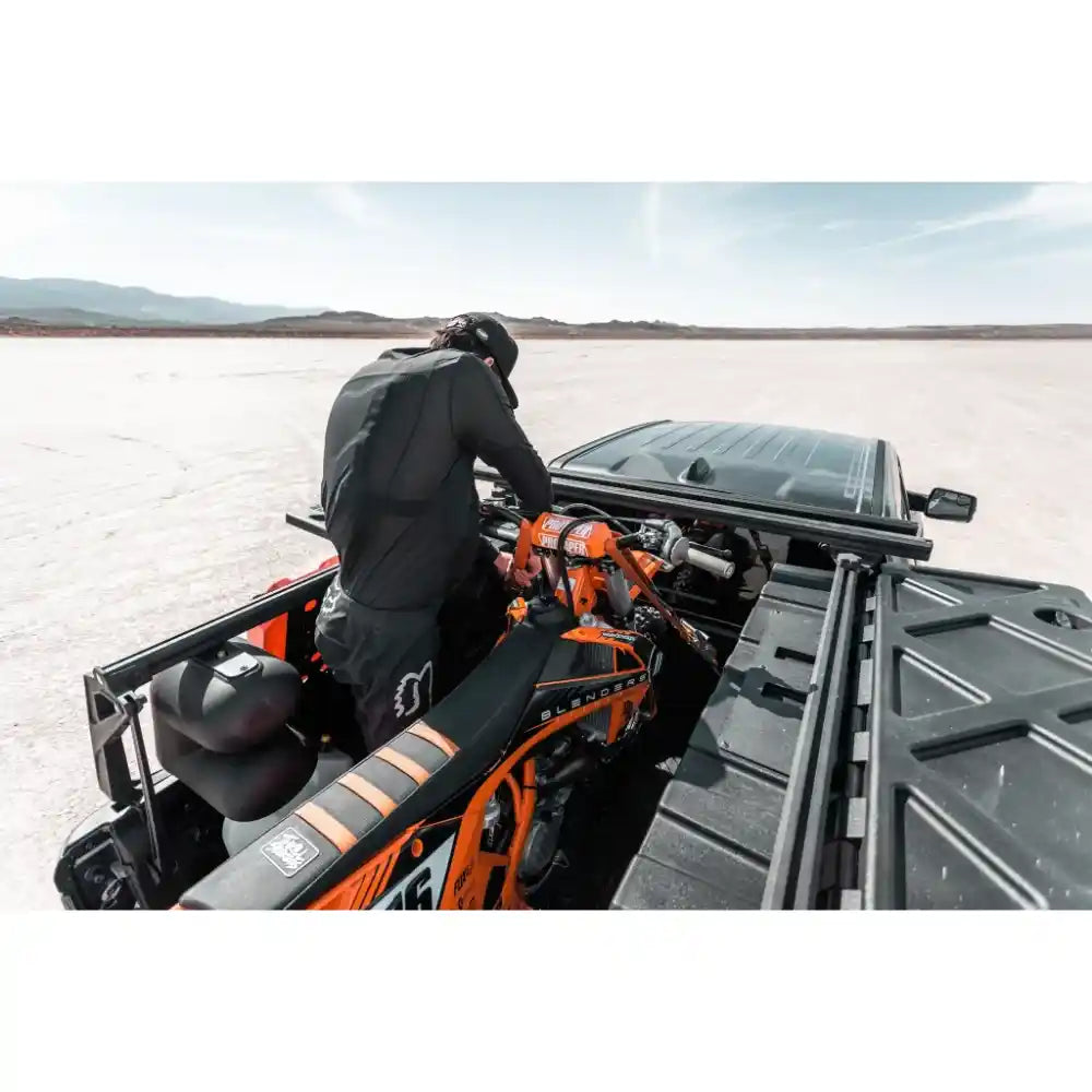 Person setting up motorbike Leitner Designs ACS FORGED NDNS Bed Rack features list.