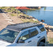Person securing surfboards atop white 4Runner's black RCI rack near scenic lakeshore