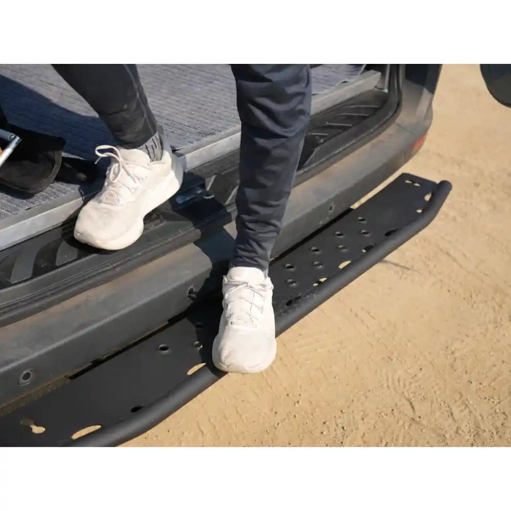 Person using a Sprinter Rear step to enter a vehicle on a sandy surface