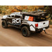 RCI Offroad Tacoma with HD bed rack loaded with bike and rooftop tent on dirt road