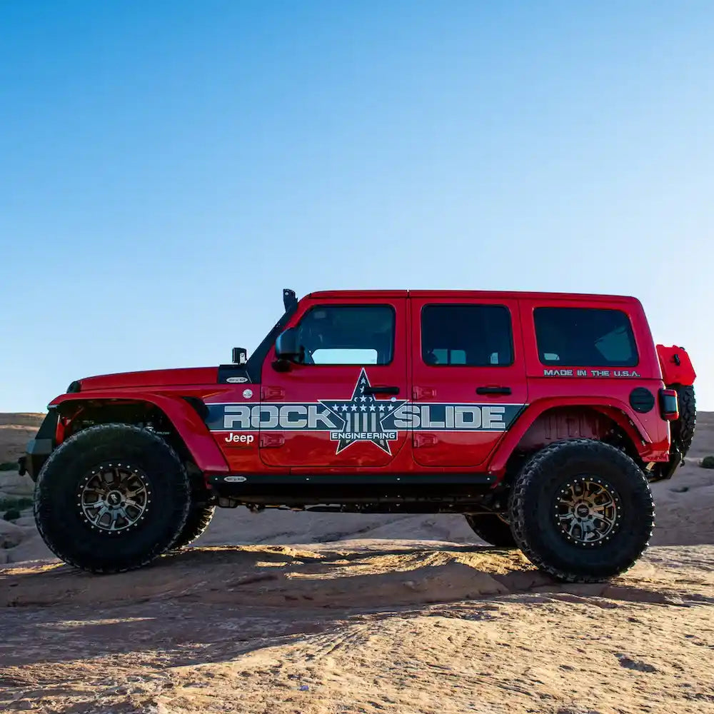 Red Wrangler JL on rocks, sliders visible