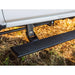 Retractable AMP PowerStep extended under a Chevrolet Silverado on off-road terrain.