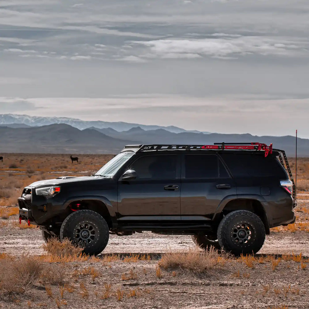 side view of Black 4runner with mounted southern  roof rack in a desert landscape with mountains in the background