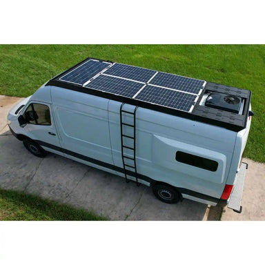Van with solar panels on the roof and a ladder on a grassy area