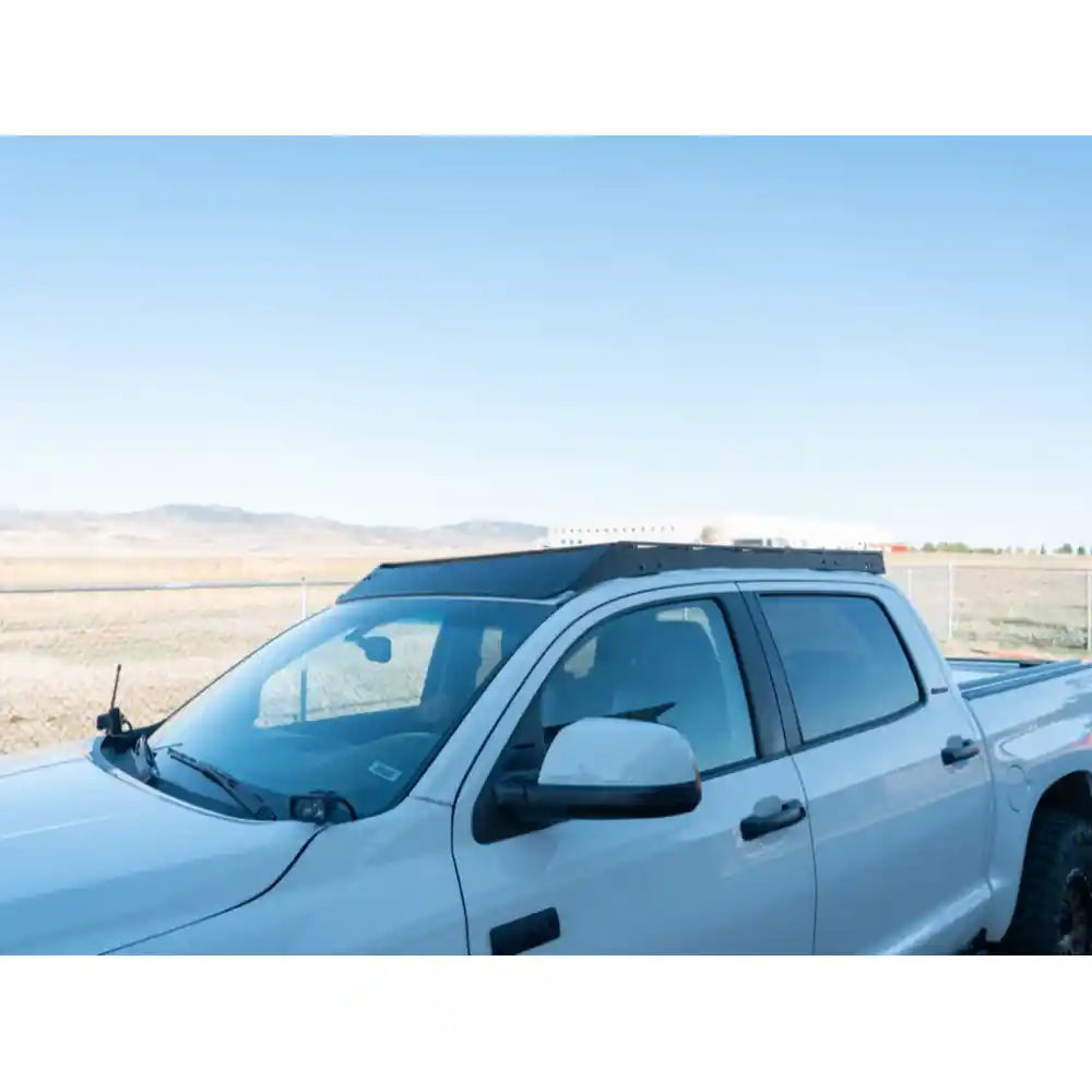 Side profile of white Tundra CrewMax with low-profile black RCI roof rack in desert setting