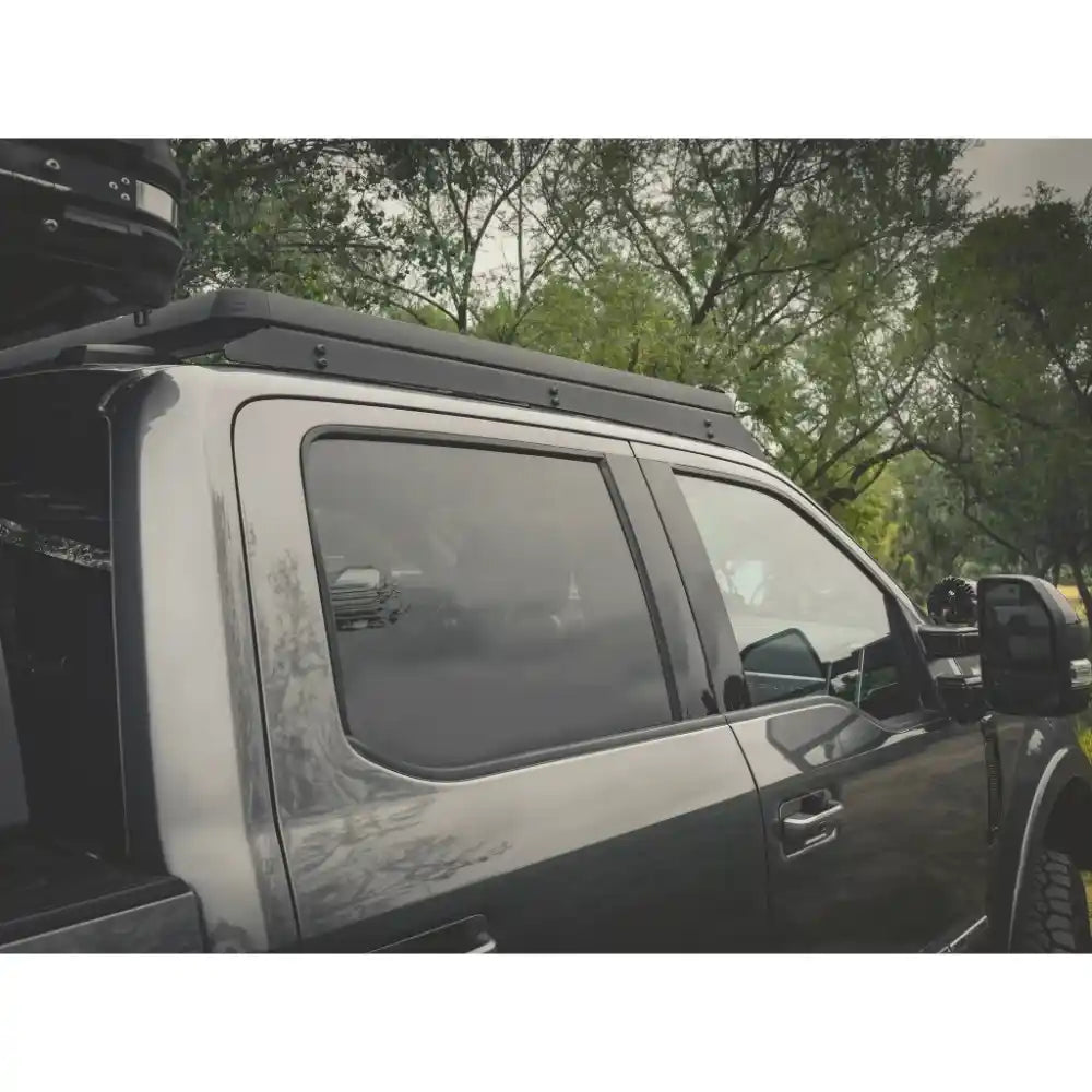 Side view of a black ford with a roof rack in a forested area