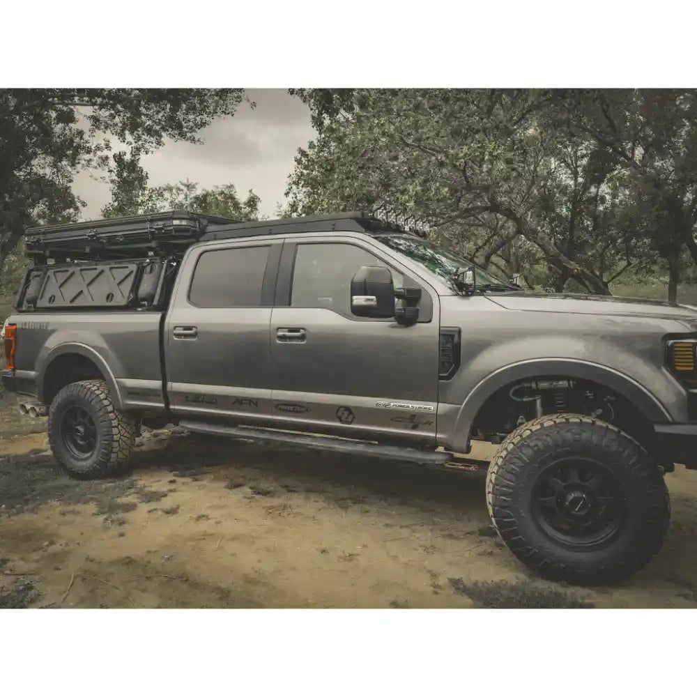 Silver pickup truck with roof rack in a forest setting