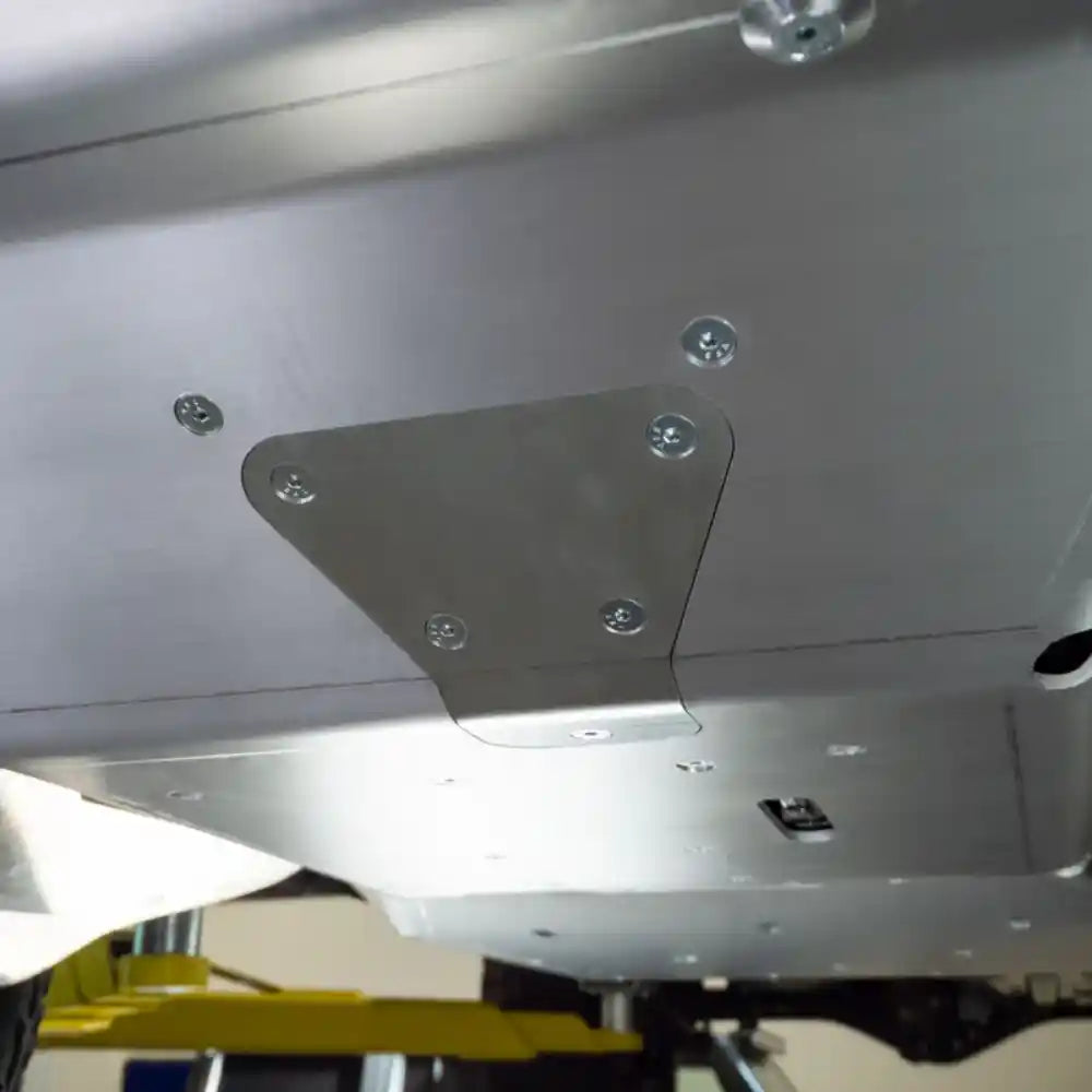 Metal bracket attached to a vehicle's skid plates with visible bolts.